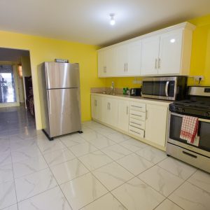 A kitchen with white cabinets and yellow walls.