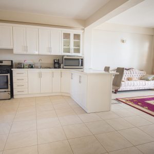 A kitchen with white cabinets and tiled floors