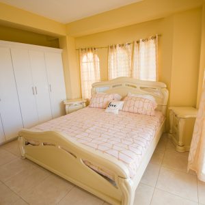 A bedroom with a bed, nightstand and closet.