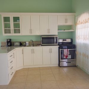 A kitchen with white cabinets and green walls.